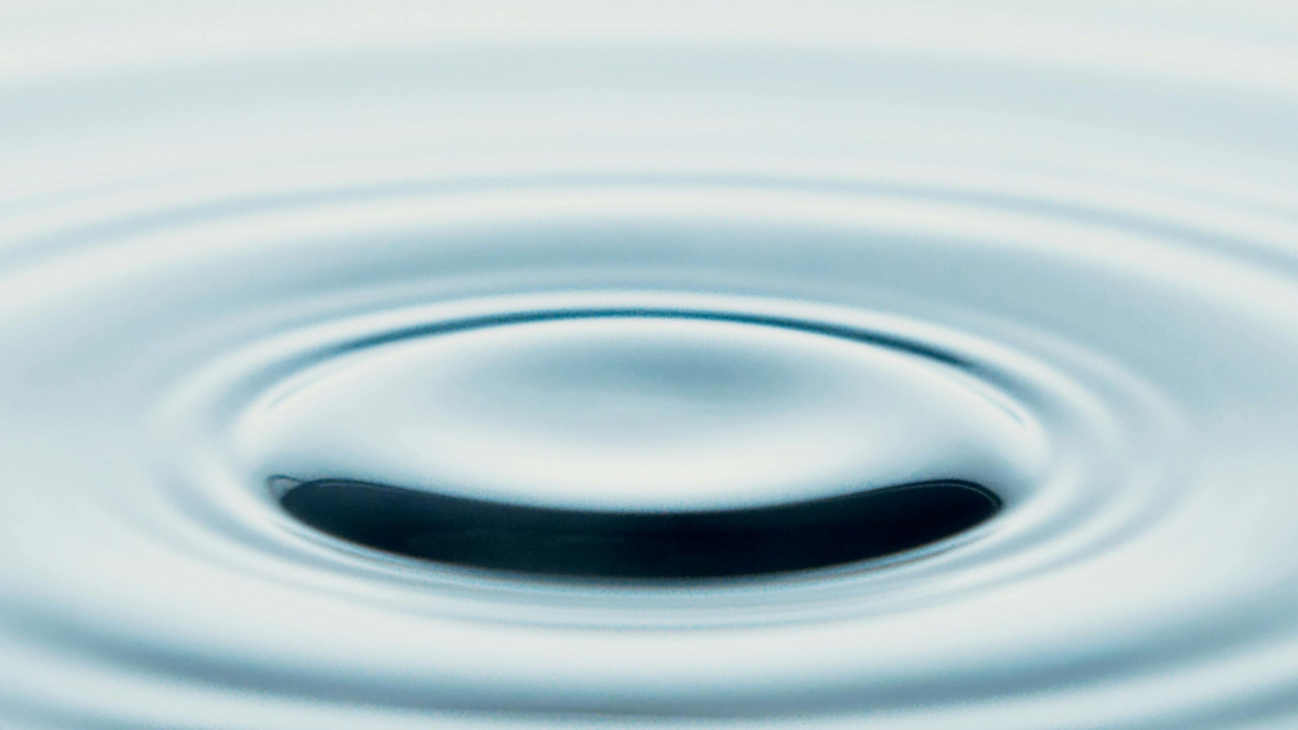 A close-up of a serene water ripple creating a minimalist abstract art piece. Ideal for tranquil designs.